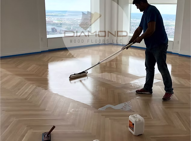 Professional flooring contractor applying finish to hardwood floors in NJ